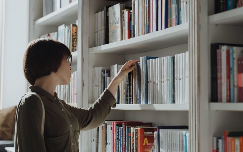Mulher escolhendo livros em uma livraria pexels